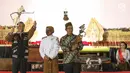 Presiden Joko Widodo (Jokowi) memainkan wayang kulit disaksikan dalang Ki Mantep Sudarsono (tengah) dalam Pagelaran Wayang Kulit 74 Tahun Indonesia Merdeka di halaman depan Istana Merdeka, Jakarta, Jumat (2/8/2019). Pagelaran wayang mengangkat tema "Kresno Jumeneng Ratu”.(Liputan6.com/Angga Yuniar)