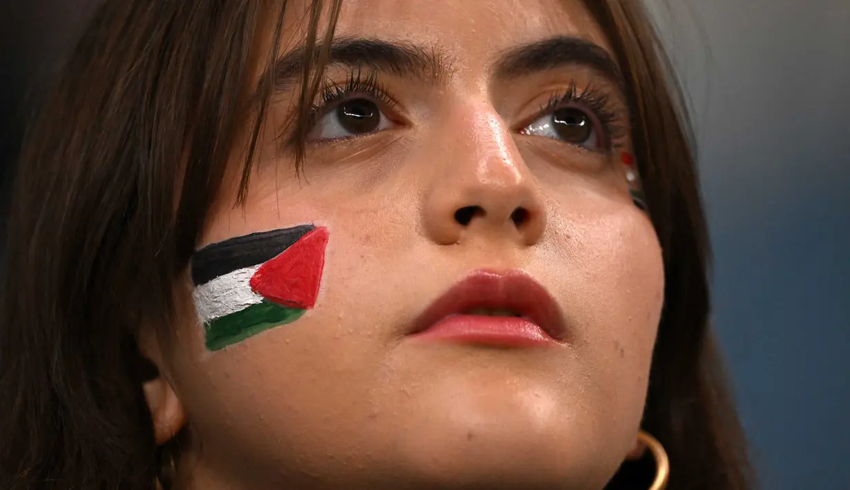 Suporter wanita mengenakan cat wajah sesaat sebelum pertandingan sepak bola Grup C Piala Asia AFC Qatar 2023 antara Palestina dan Uni Emirat Arab di Stadion Al-Janoub di Al-Wakrah, Doha pada 18 Januari 2024. (HECTOR RETAMAL/AFP)