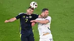 Gelandang Skotlandia #07 John McGinn menyundul bola di samping bek Swiss #22 Fabian Schaer pada duel matchday 2 Grup A Euro 2024 di Stadion Rhein Energie, Kamis (20/6/2024) dini hari WIB. (Kirill KUDRYAVTSEV / AFP)