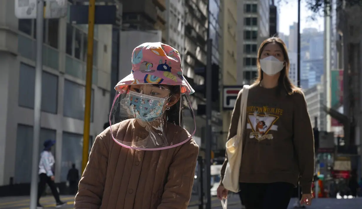 Seorang gadis mengenakan masker dan pelindung wajah saat berjalan di Hong Kong, 8 Maret 2022. COVID-19 varian Omicron yang menyebar cepat membanjiri Hong Kong membuat kamar jenazah penuh, memaksa pihak berwenang untuk menyimpan jenazah dalam kontainer pengiriman berpendingin. (AP Photo/Kin Cheung)