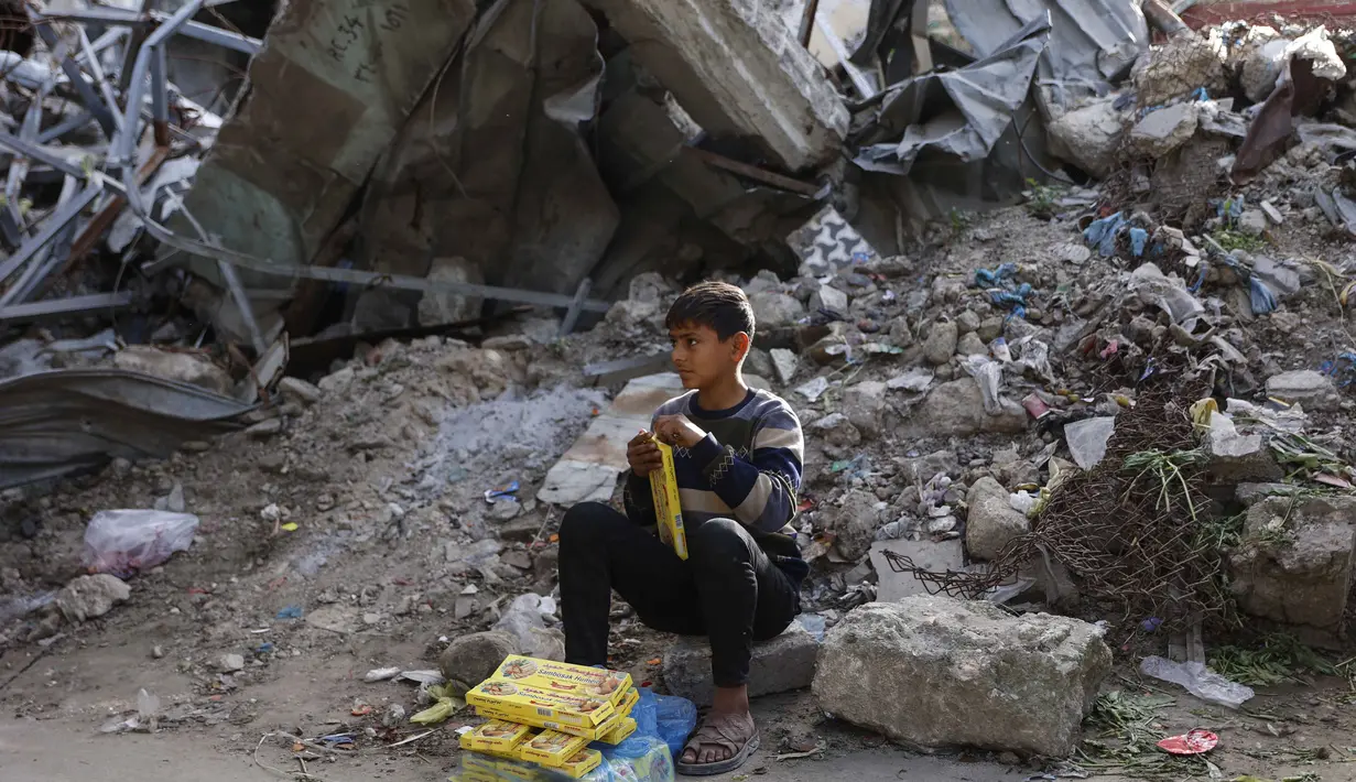 Untuk mencapai Pasar Al-Zawiya, warga harus berjalan melewati reruntuhan bangunan akibat konflik antara Israel dan Hamas. Tampak dalam foto, seorang pemuda Palestina duduk di reruntuhan di pasar Zawiya, Kota Gaza, pada Rabu 18 Februari 2026. (Omar AL-QATTAA/AFP)