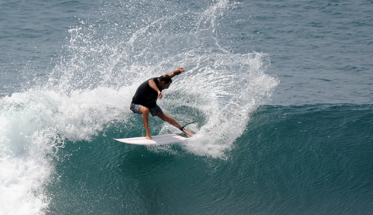 Turis beraksi di atas ombak saat bermain selancar di pantai Uluwatu Kuta Selatan di Kabupaten Badung, Bali pada 20 Desember 2018. Di Bali, terdapat banyak pantai yang merupakan lokasi ideal untuk kegiatan berselancar. (Photo by SONNY TUMBELAKA / AFP)