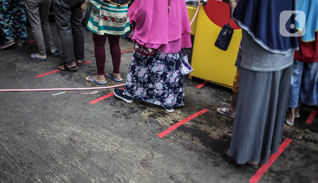 Pengunjung menerapkan jaga jarak aman saat akan masuk Pasar Kebayoran Lama, Jakarta Selatan, Senin (22/6/2020). Pasar Kebayoran Lama kembali buka setelah sebelumnya tutup selama tiga hari sejak 18 Juni 2020 akibat 14 pedagang positif COVID-19. (Liputan6.com/Faizal Fanani)