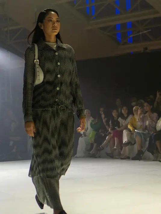 Setelan hitam dengan atasan lengan panjang dan rok plisket juga dihadirkan IKYK. [@ikyk2011]