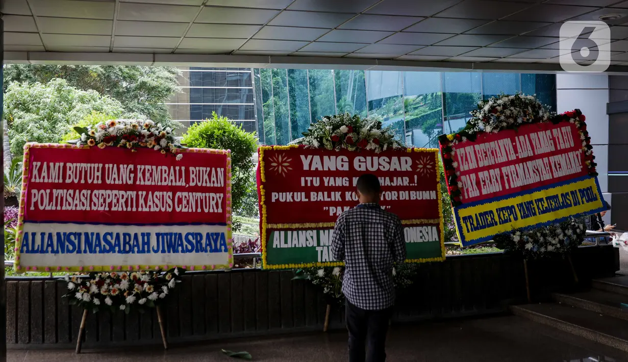 Seorang pria berdiri di depan karangan bunga dukungan di halaman Kementerian BUMN Jakarta, Kamis (16/1/2020). Kantor Menteri BUMN Erick Thohir kembali mendapat kiriman bunga berupa dukungan untuk menyelesaikan masalah PT Asuransi Jiwasraya (Persero). (Liputan6.com/Faizal Fanani)