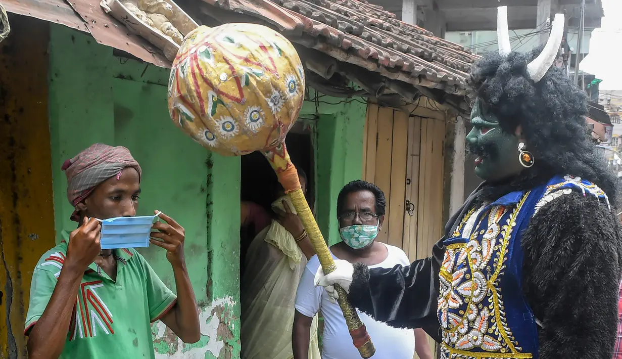 Seorang pria berkostum dewa kematian Yamaraj saat mengimbau warga yang tidak memakai masker di tengah lockdown di Kolkata, India (24/4/2020). (AFP/Dibyangshu Sarkar)