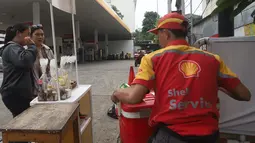 Warga membeli minuman dingin yang dijajakan karyawan atau petugas Stasiun Pengisian Bahan Bakar Umum (SPBU) di depan SPBU Shell, Jalan Gunung Sahari, Jakarta, Kamis (18/9/2025). (merdeka.com/Arie Basuki)