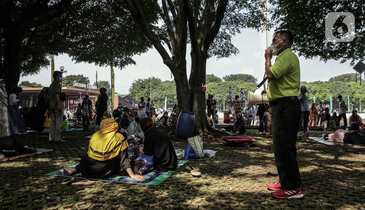 Petugas melakukan sosialisasi protokol kesehatan kepada para pengunjung yang berwisata di Taman Mini Indonesia Indah (TMII), Jakarta, Sabtu (15/5/2021). Jumlah pengunjung dibatasi hanya 30 persen dari kapasitas normal dan hanya warga beridentitas DKI yang boleh masuk. (Liputan6.com/Faizal Fanani)