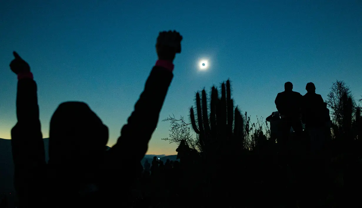 Orang-orang melihat gerhana matahari total dari La Higuera, Chile, Selasa (2/7/2019). Orang-orang bersorak dan bertepuk tangan saat cakram bulan menutup matahari. (AP Photo/Esteban Felix)