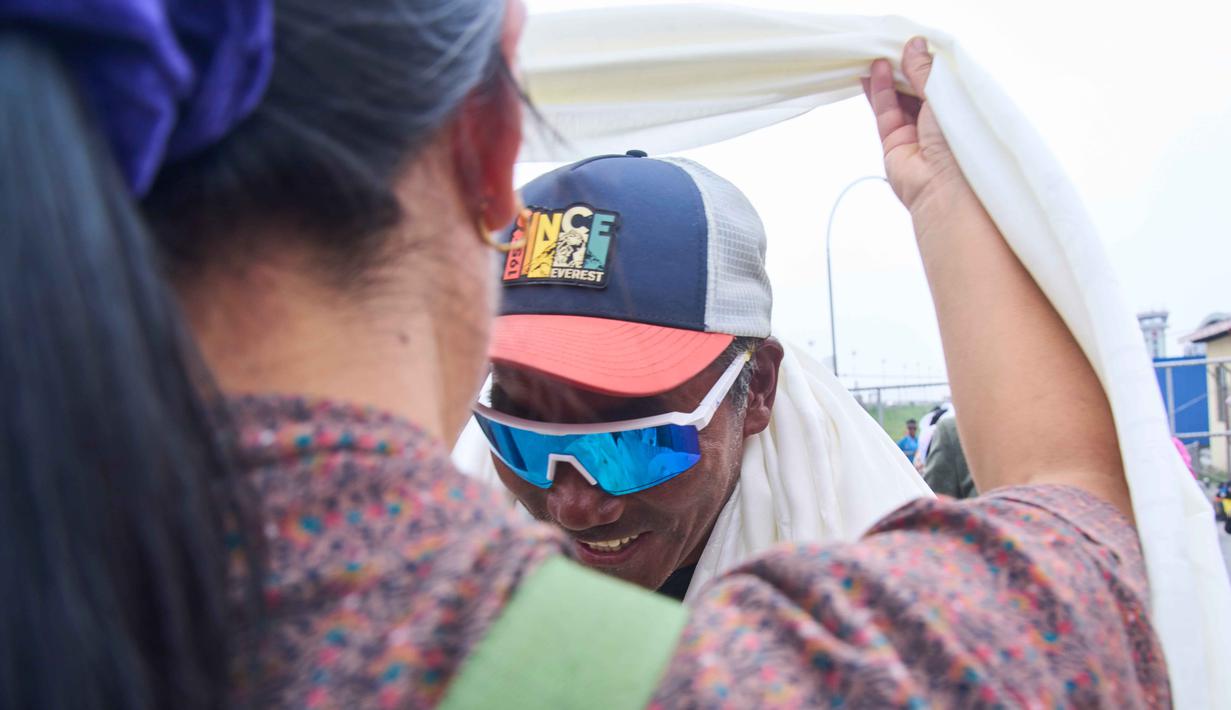 Pemandu gunung legendaris asal Nepal, Kami Rita Sherpa, yang kembali dari Gunung Everest setelah pendakiannya yang ke-32, menerima selendang saat tiba di bandara, Kathmandu, Nepal, Jumat 22 Mei 2026. (AP Photo/Niranjan Shrestha)