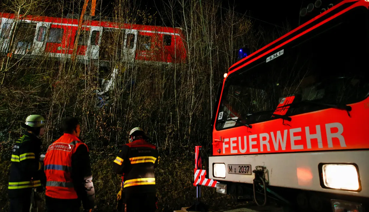 Petugas mengevakuasi rangkaian kereta komuter S-bahn yang tabrakan di Schaeftlarn di distrik Munich, Jerman pada 14 Februari 2022. Lebih dari 200 tim penyelamat dan polisi diterjunkan ke lokasi kecelakaan. (MICHAELA REHLE / AFP)