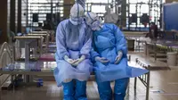 Dua staf medis dari Provinsi Qinghai, China barat laut, beristirahat sebelum meninggalkan rumah sakit sementara Wuchang di Wuhan, Provinsi Hubei, China tengah (10/3/2020). Tema yang dipilih Dewan Perawat Internasional pada peringatan tahun ini adalah "Merawat Dunia agar Sehat". (Xinhua/Fei Maohua)