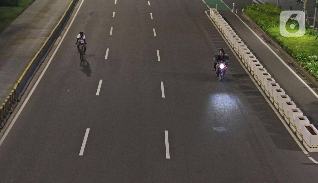 Warga bersepeda di jalan lengang kawasan Sudirman, Jakarta, Rabu (12/5/2021) malam. Polda Metro Jaya memberlakukan crowd free night untuk mencegah kerumunan takbir keliling di malam Idul Fitri 1442 yang berlaku mulai pukul 22:00 malam ini. (Liputan6.com/Herman Zakharia)
