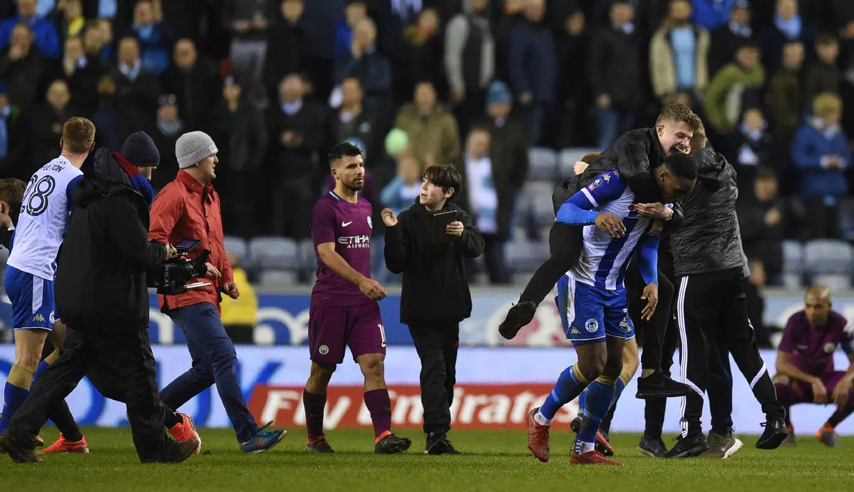 Seorang suporter mendekati Striker Manchester City Sergio Aguero dari belakang dan terlihat berusaha mengatakan sesuatu seusai babak kelima Piala FA di markas Wigan Athletic, Stadion DW, Senin (19/2). Hal itu memancing kemarahan Aguero. (Oli SCARFF/AFP)