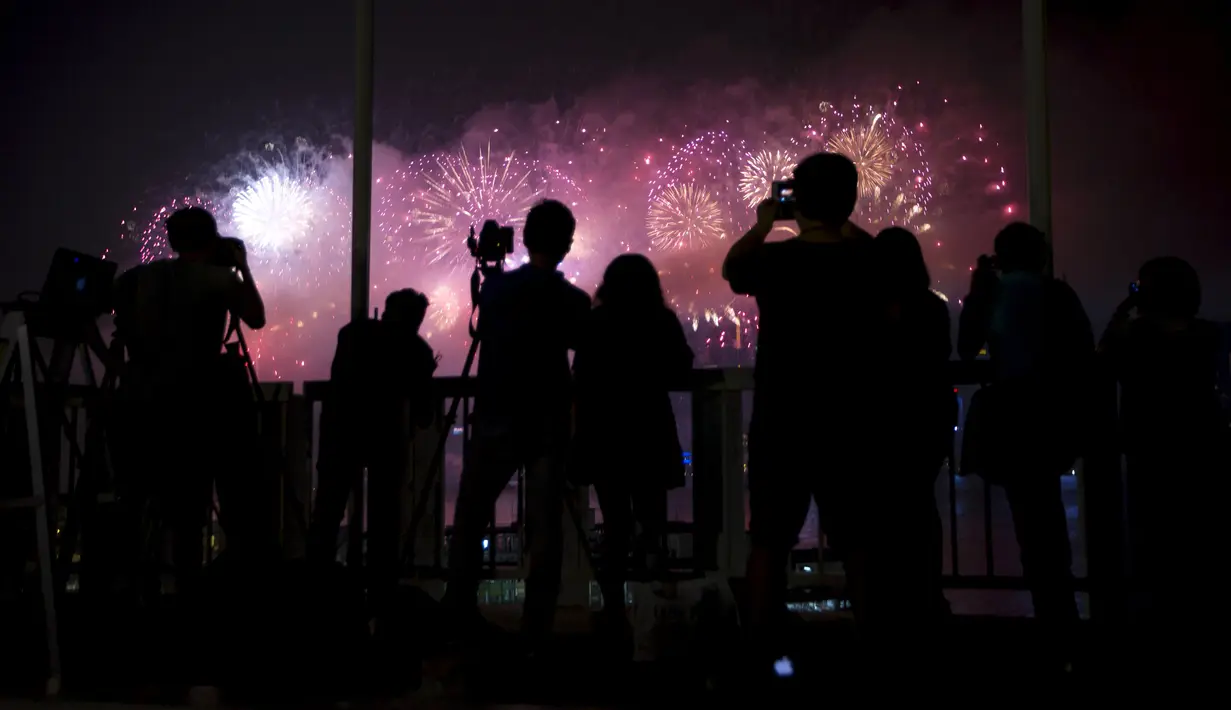 Fotografer mengambil gambar saat kembang api menghiasi Dermaga Victoria, Hong Kong, dalam rangka peringatan ulang tahun ke-66 Republik Rakyat China, Kamis (1/10/2015). (REUTERS/Tyrone Siu)