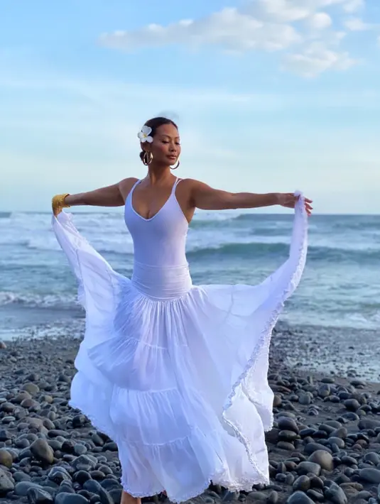 Serba putih, penampilan Indah Kalalo kali ini menggambarkan dirinya sebagai putri laut. Fitted dress dengan potongan bohemian di bagian bawah membuatnya tampil eksostis berfoto di pinggir pantai. (Instagram/indahkalalo)