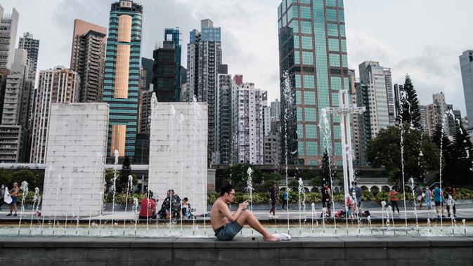 Seorang pria duduk di sebelah air mancur di Taman Peringatan Sun Yat Sen di Hong Kong (21/4/2020). Hong Kong melaporkan penurunan kasus infeksi harian Covid-19, tetapi pemerintah kota mengatakan mereka tidak mengambil risiko apa pun. (AFP/Anthony Wallace)