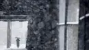 Seorang wanita menggunakan payung berjalan di bawah salju lebat saat terjadi badai salju di Hoboken, New Jersey (21/3). Karena badai salju yang melanda New Jersey ini layanan komuter dan bus dihentikan pada pukul 3 sore. (AP/Julio Cortez)
