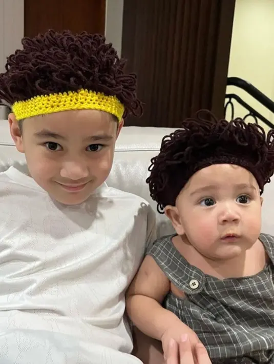 Momen menggemaskan kembali terlihat saat Rayyanza memakai wig rambut keriting ketika bersama sang kakak. Momen kekompakan anak Nagita dan Raffi ini membuat warganet merasa gemas. Ekspresi Rayyanza yang lucu menjadi daya tarik foto ini. (Liputan6.com/IG/raffinagita1717)