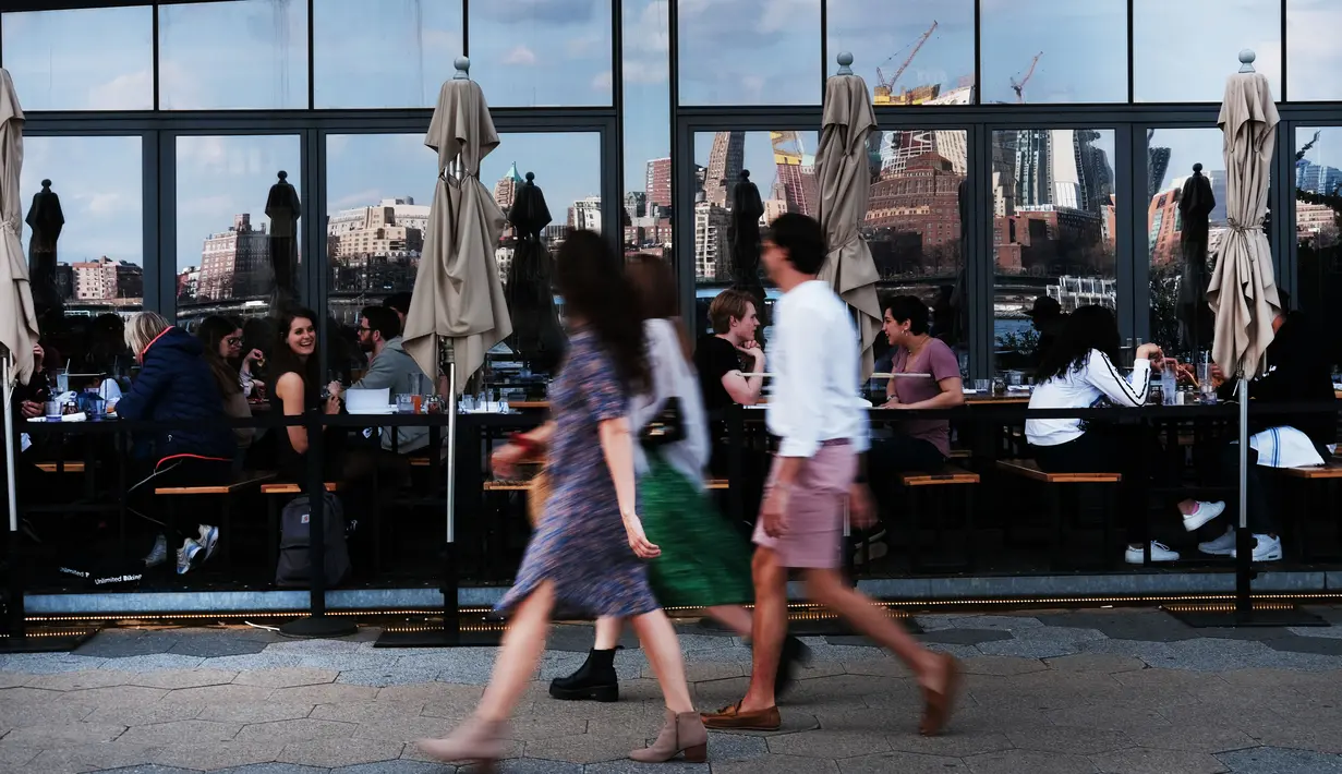 Orang-orang menikmati makanan di restoran selama musim semi yang hangat di tepi air di Manhattan di New York City (8/4). Sebagian besar Pantai Timur mengharapkan suhu hangat terus sepanjang minggu. (Spencer Platt/Getty Images/AFP)