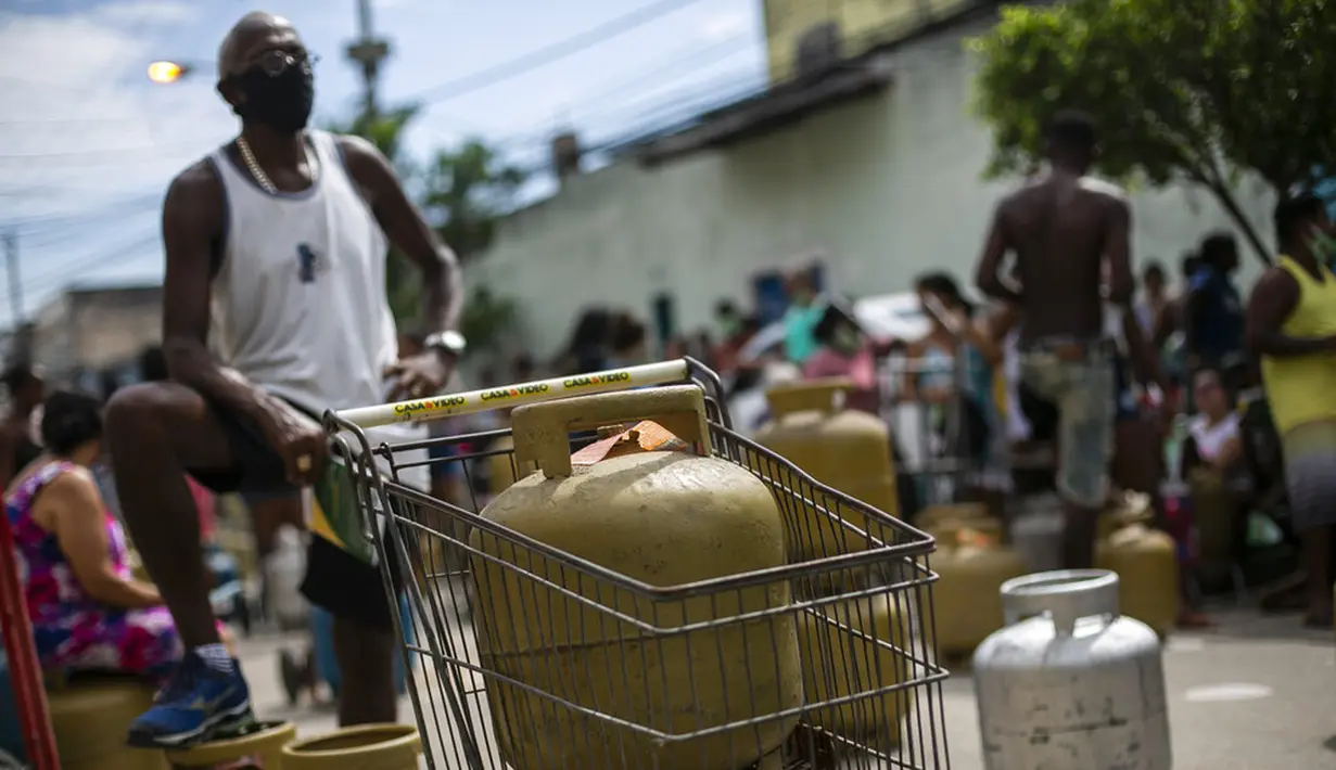 Warga memakai masker saat antre membeli gas murah dari Petrobrás Oil Tankers Union di favela Vila Vintem, Rio de Janeiro, Brasil, Jumat (12/3/2021). Kegiatan ini sebagai kampanye solidaritas untuk memperingati Hari Perjuangan Nasional Pertahanan Perusahaan Milik Negara. (AP Photo/Bruna Prado)