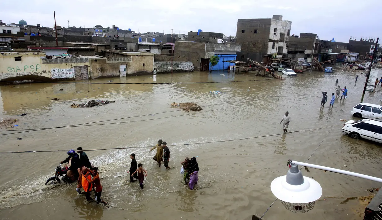 Warga melintasi jalan yang banjir setelah hujan deras di Karachi, Pakistan, Selasa (30/7/2019). Hujan deras terjadi pada hari Senin dan berlanjut pada hari Selasa dan air limbah membanjiri sebagian besar jalan di Karachi, ibukota provinsi Sindh selatan. (AP/Photo/Fareed Khan)