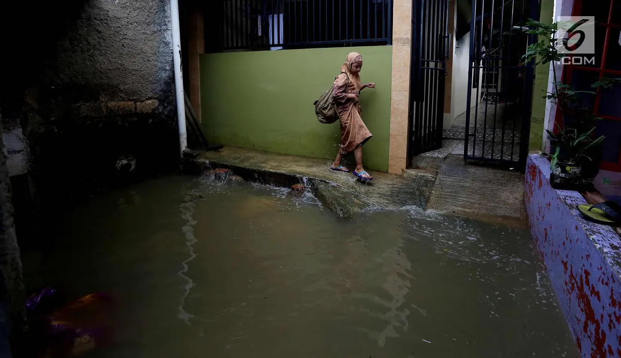 Seorang anak melintasi banjir di permukiman Jati Padang, Jakarta, Kamis (30/11). Banjir yang terjadi tersebut akibat tanggul darurat di Kali Pulo jebol karena genangan air yang cukup deras dan membanjiri Permukiman Sekitar. (Liputan6.com/Johan Tallo)