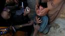 Seorang anak dipegangi orang tuanya saat petugas memberikan imunisasi polio di sepanjang jalan di Quetta, Pakistan, Senin (2/1). (REUTERS/Naseer Ahmed)