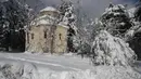 Sebuah gereja Ortodoks Yunani tertutup salju setelah hujan salju lebat di Dionysos, Athena, Yunani, Rabu (17/2/2021). Fenomena salju yang tak biasa ini mengakibat layanan transportasi terganggu. (AP Photo/Thanassis Stavrakis)
