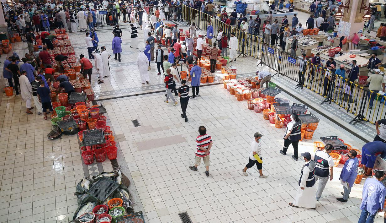 Orang-orang berbelanja selama pelelangan di pasar ikan di Kuwait City (8/8/2021). Pelelangan dibuka kembali di negara itu setelah enam bulan ditutup di tengah pandemi virus corona. (AFP/ Yasser Al-Zayyat)