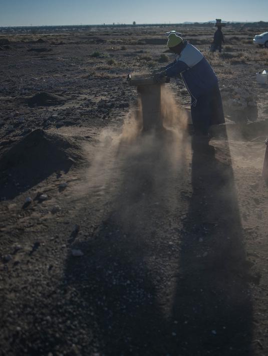 Seorang wanita lansia, Clara Maitse mengayak tanah untuk mencarai berlian di Kimberley, Northern Cape, Afrika Selatan (5/6). Clara Maitse adalah seorang wanita berusia 77 tahun yang merupakan bekas penambang ilegal. (AFP/Mujahid Safodien)
