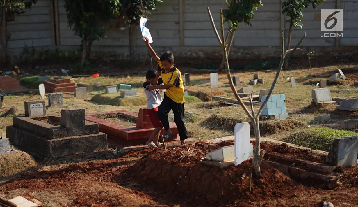 Anak-anak bermain di sekitar Taman Pemakaman Umum (TPU) Karet Bivak, Jakarta, Selasa (10/9/2019). Keterbatasan ruang terbuka hijau memaksa sebagian anak-anak di Ibu Kota bermain tidak pada tempatnya, meskipun dalam kondisi yang tidak layak. (Liputan6.com/Immanuel Antonius)