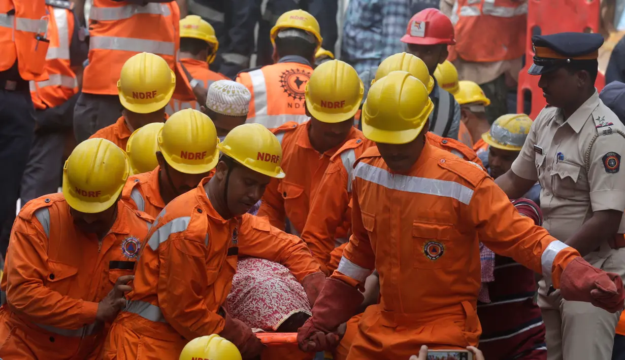 Petugas penyelamat membawa jenazah korban runtuhnya bangunan di Mumbai, India (31/8). Pemerintah kota Mumbai mengatakan sedikitnya sembilan orang tewas dalam peristiwa tersebut. (AP Photo / Rafiq Maqbool)