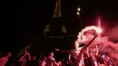 Para pendukung Paris Saint-Germain (PSG) menyalakan suar di depan Menara Eiffel, Paris, Prancis pada 31 Mei 2025 waktu setempat atau Minggu 1 Juni 2025 dini hari WIB. (Thibaud MORITZ/AFP)