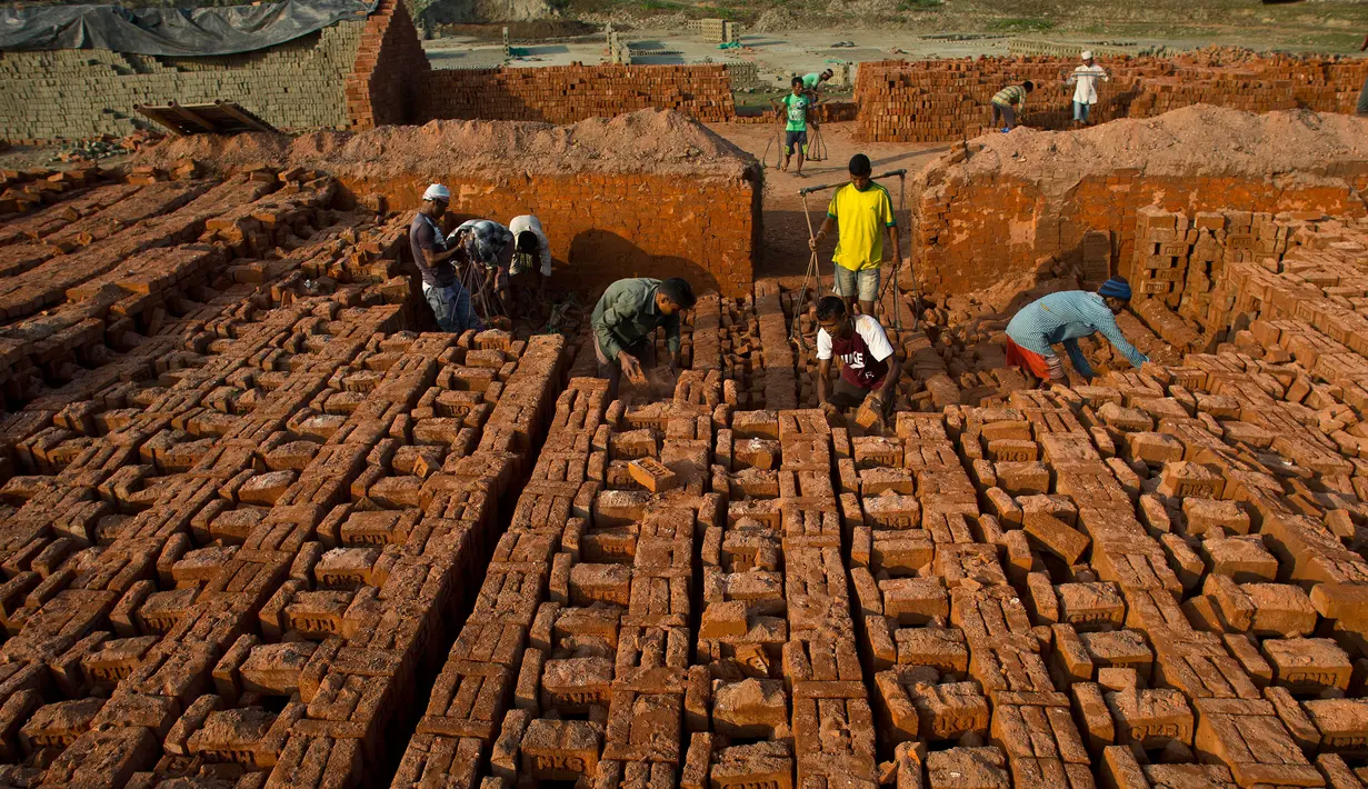 Pekerja India bekerja di sebuah tempat pembakaran batu bata di pinggiran Gauhati, India (22/11). Sebagian besar buruh di sini mendapatkan Rupee 120 (kurang dari 2 Dolar) per hari. (AP Photo/Anupam Nath)
