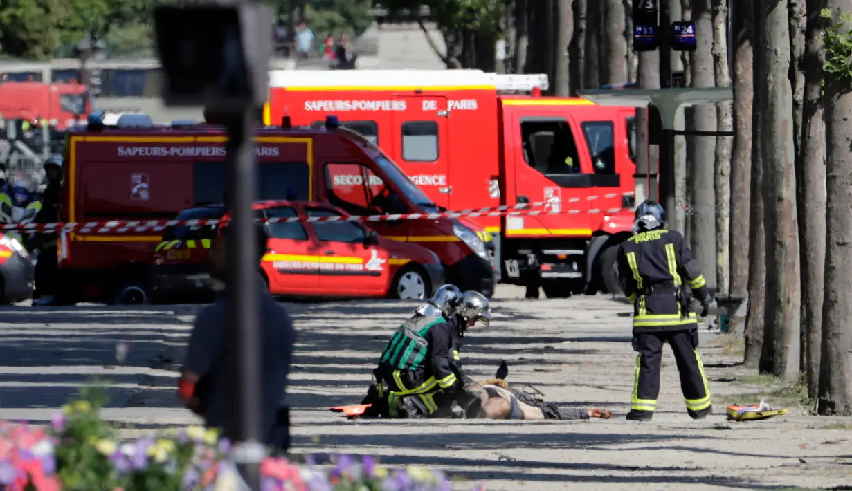 Petugas penyelamat disamping jasad seorang pria usai serangan terhadap van polisi di jalan Champs Elysees, Paris, Senin (19/6). Pria 31 tahun tersebut tewas, sementara pihak kepolisian yang menjadi target tak terluka sedikitpun. (Thomas SAMSON/AFP)