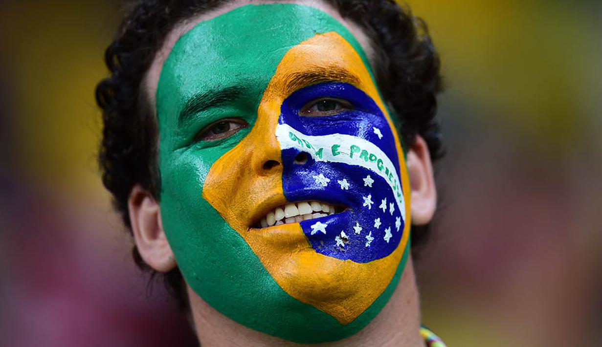 Supporter Brasil mewarnai wajahnya saat menonton laga kualifikasi Piala Dunia 2018 melawan Uruguay di Recife, Brasil, Sabtu (26/3/2016) pagi WIB. Kedua tim bermain imbang 2-2. (AFP/Christophe Simon)