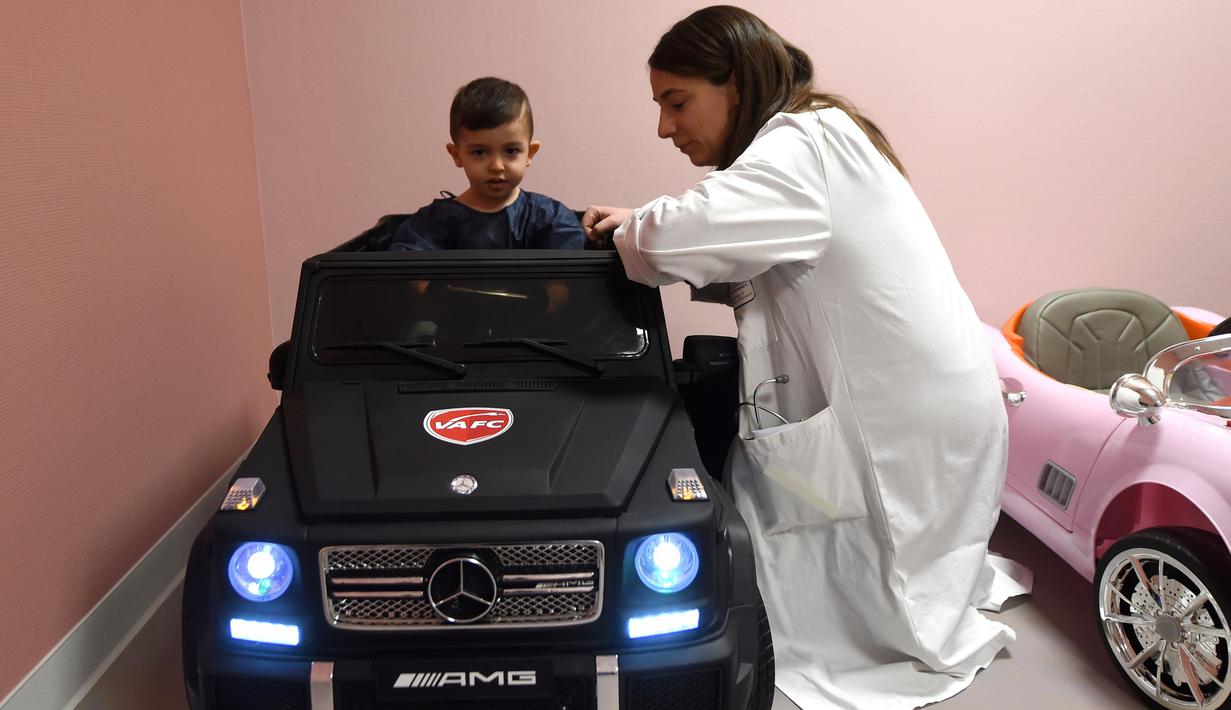 Petugas medis membantu Souvail (2) duduk di mobil mainan listrik menuju ruang operasi di Rumah Sakit Valenciennes, Prancis, Jumat (2/2). Program ini untuk membuat anak-anak lebih santai sebelum menjalani prosedur operasi. (FRANCOIS LO PRESTI/AFP)
