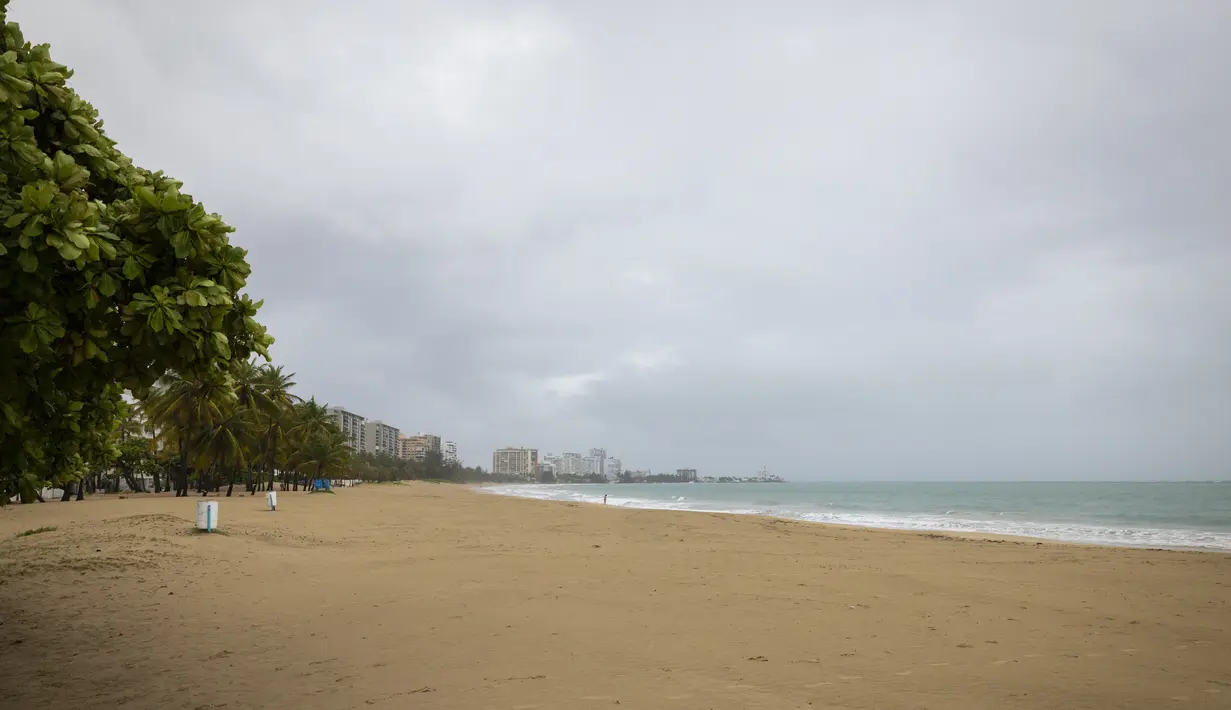 Seorang perempuan berjalan di pantai yang kosong sebelum kedatangan Badai Tropis Fiona di San Juan, Puerto Rico, Sabtu (17/9/2022). Setelah dari Puerto Rico, Fiona diproyeksikan melintasi Republik Dominika pada Senin mendatang dengan ancaman hujan deras yang berpotensi memicu banjir bandang atau longsor. (AP Photo/Alejandro Granadillo)
