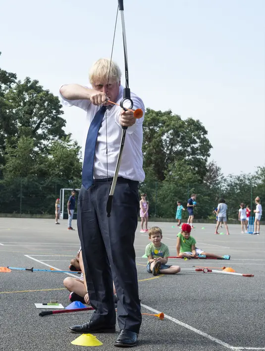 PM Inggris Boris Johnson bermain panahan saat mengunjungi Premier Education Summer Camp di Sacred Heart of Mary Girl's School, Upminster, Inggris, Senin (10/8/2020). Kunjungan Boris untuk melihat persiapan jelang pembukaan kembali sekolah pada September mendatang. (Lucy Young/Pool via AP)