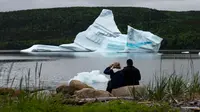 Wisatawan menyaksikan pemandangan gunung es terapung dekat King's Point, Newfoundland, Kanada, 3 Juli 2019. Gunung es terapung memberi pemandangan kontras yang unik, terutama bagi penggemar fotografi. (Johannes Eisele/AFP)