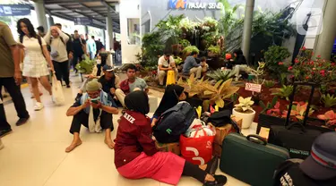 Calon pemudik yang akan menggunakan Kereta Api Jarak Jauh duduk di lantai menanti waktu keberangkatan di Stasiun Pasar Senen, Jakarta, Minggu (7/4/2024). (Liputan6.com/Helmi Fithriansyah)