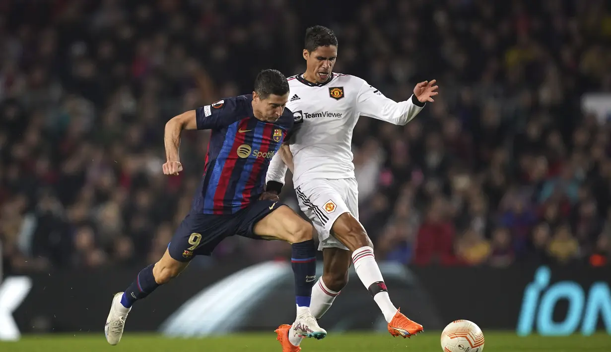 Bek Manchester United (MU) Raphael Varane berebut bola dengan penyerang Barcelona Robert Lewandowski pada leg pertama play-off babak gugur Liga Europa 2022/2023 di Camp Nou, Jumat (17/2/2023) WIB. Man United sendiri mencetak dua gol di antaranya, masing-masing lewat Marcus Rashford (53') dan bunuh diri Jules Kounde (59'). AP Photo/Joan Mateu Parra)