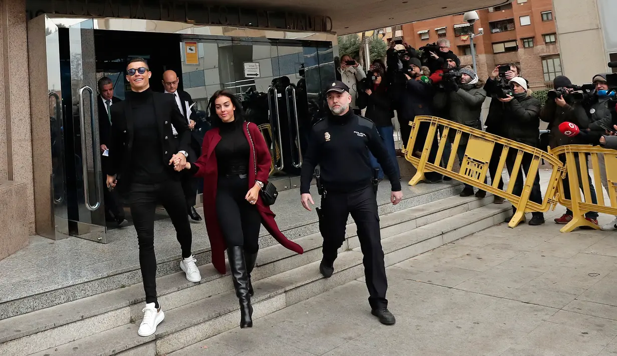 Pemain Juventus Cristiano Ronaldo menggandeng kekasihnya Georgina Rodriguez meninggalkan pengadilan di Kota Madrid, Spanyol, Selasa (22/1). Ronaldo diduga menggelapkan pajak dalam rentang waktu 2011-2014. (AP Photo/Manu Fernandez)