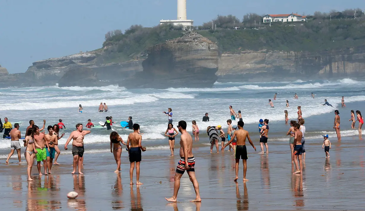 Orang-orang berjalan di pantai Port Vieux, (Old Seaport) di Biarritz, barat daya Prancis, (19/4). Suhu di Prancis barat daya telah mencapai 27 derajat Celcius (80,6 Fahrenheit). (AP Photo / Bob Edme)