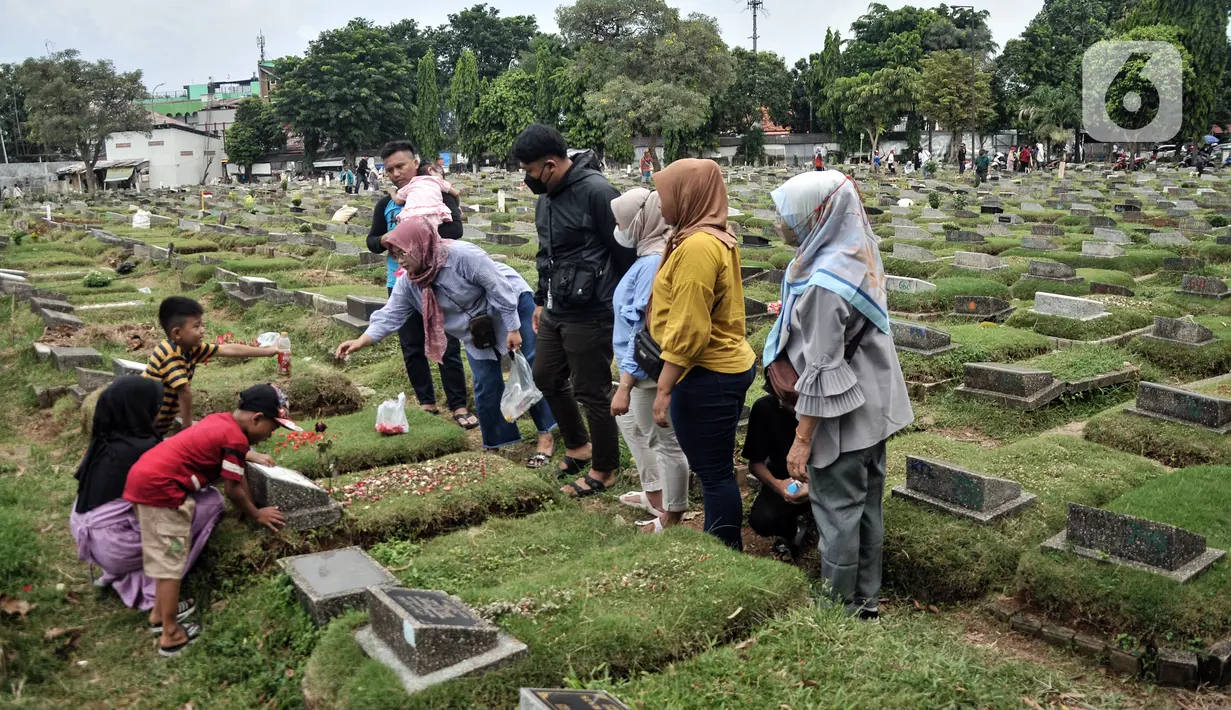 Sekelompok warga menaburkan bunga ke atas salah satu makam kerabat di TPU Kemiri. (merdeka.com/Iqbal S. Nugroho)