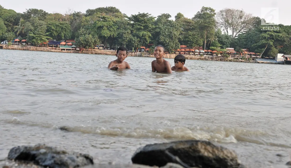 Anak-anak berenang di Danau Sunter, Jakarta, Selasa (23/7/2019). Minimnya fasilitas bermain yang layak dan murah membuat anak-anak nekat berenang di Danau Sunter. (merdeka.com/Iqbal Nugroho)