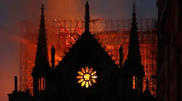 Api dan asap mengepul dari kebakaran Gereja Katedral Notre-Dame di pusat kota Paris, Prancis, pada Senin (15/4) waktu setempat. Api dengan cepat melalap bagian atap gereja yang dibangun pada abad ke-12 itu dan merupakan salah satu ikon wisata di Paris. (AP Photo/Thibault Camus)