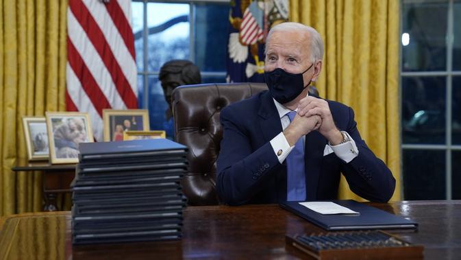 Presiden AS Joe Biden menunggu untuk menandatangani tindakan eksekutif pertamanya di Ruang Oval, Gedung Putih, Washington D.C pada Rabu (20/1/2021). (Photo credit: AP/Evan Vucci)