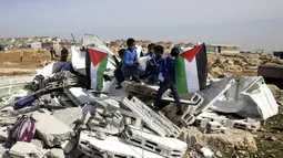 Anak-anak bermain di antara puing-puing sekolah mereka yang hancur di Desa Abu Nuwar, Tepi Barat, Palestina, Minggu (4/2). Israel menghancurkan sekolah mereka karena menganggap bangunan yang didanai Uni Eropa itu ilegal. (AP Photo/Mahmoud Illean)